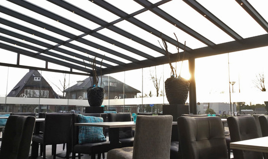 Horeca veranda serre met geïntegreerde zonwering, spiekozijn en glazen schuifwanden.